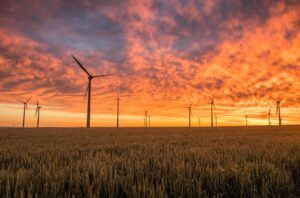 landscape-photography-of-grass-field-with-wind-turbines-under-orange-sunset